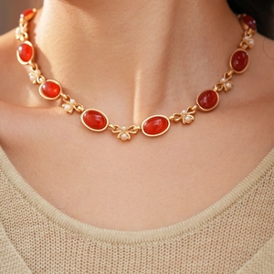 Nahaufnahme der Vintage Goldhalskette mit ovalen roten Steinen und weißen Perlen am Hals