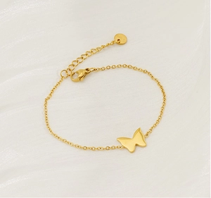 Detailed close-up of a gold butterfly bracelet on a soft white silk fabric background