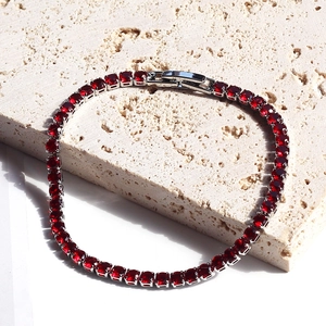 Macro view of silver tennis bracelet featuring square-cut deep red zircons and fold-over clasp