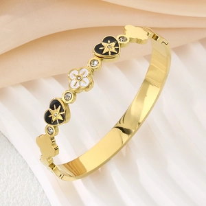 Macro shot of gold-plated clover and heart charms with zircon inlay on an elegant bangle