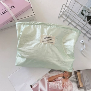Flat lay of stylish mint green pleated cosmetic bag on desk with lifestyle accessories