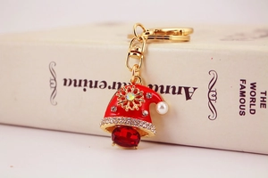 Macro shot of snowman keychain with red enamel hat, crystals, and gold snowflake pendant