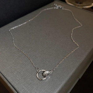 Detailed view of silver interlocking double ring pendant with cubic zirconia inlay