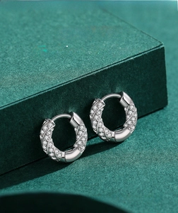 Macro shot of silver pavé hoop earrings with sparkling cubic zirconia on green velvet