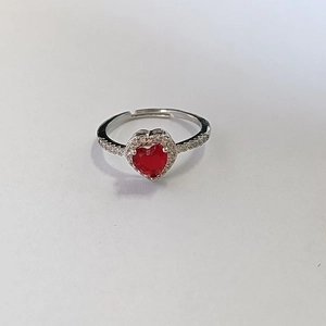 Close-up of red heart-shaped gemstone ring with silver band and micro-inlaid diamonds