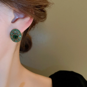 Macro shot of vintage emerald oval stud earrings with gold finish and crystal details