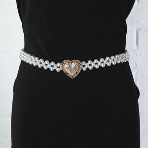 Close-up of pearl waist chain with a gold heart-shaped buckle on a black dress
