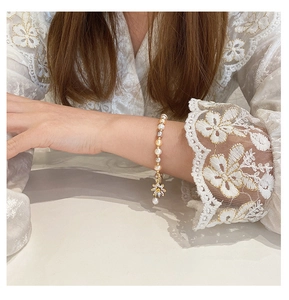 Detail of freshwater pearl bracelet featuring a zircon-encrusted sunflower charm on wrist