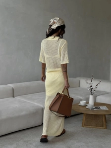 Detailed view of pale yellow knit two-piece set with elegant openwork skirt and top