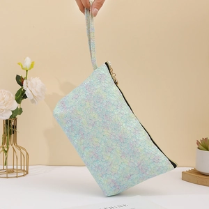 Close-up of holographic sequin makeup bag with handle in pastel blue and purple tones