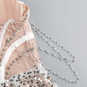 Detail view of silver sequins and white pearls on sheer mesh fabric of a sexy dress