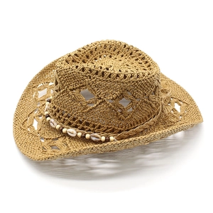 Détail du chapeau de cow-boy en paille tressée avec motifs ajourés et ruban de coquillages