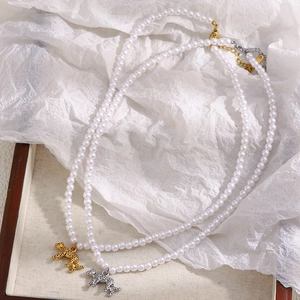 Flat lay of two pearl necklaces with gold and silver tiger pendants on white paper
