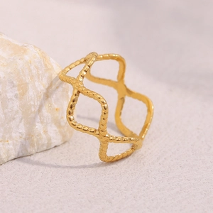 Close-up of golden geometric woven ring with granular texture on a white rock