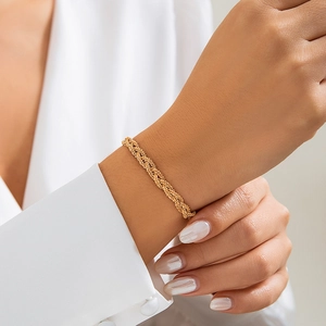Detail of a layered golden braided necklace on a white shirt sleeve for a minimalist look