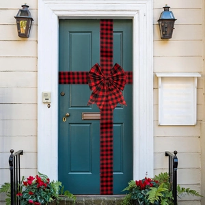 Detail of red and black buffalo plaid ribbon bow hung on a dark green front door