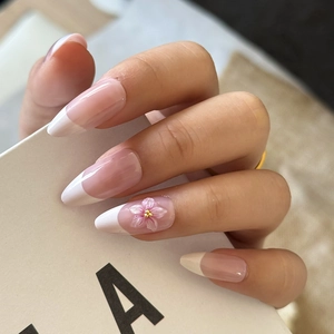 Close-up of almond-shaped French press-on nails with 3D flower and golden beads