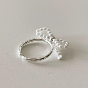 Detailed view of silver bow ring featuring white faux pearls and an adjustable open band