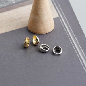 Macro shot of polished S925 sterling silver huggie earrings in gold and silver finish