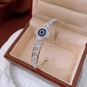 Macro shot of silver zircon floral open bangle with evil eye design in a jewelry box