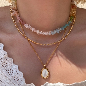Detail of bohemian layered necklace with colorful stone beads and golden oval pendant