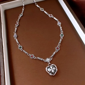 Detailed macro of silver necklace featuring colorful gems and heart-cross pendant