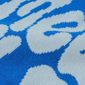 Macro detail of the blue and light gray jacquard knit pattern with premium acrylic texture