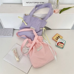 Detail of canvas tote bags in purple and pink with drawstring closures and wide straps