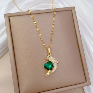 Elegant gold dolphin necklace with green heart gem and zircon inlay on velvet display