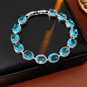 Close-up of silver chain bracelet with 14 oval sky blue zircons on black leather box