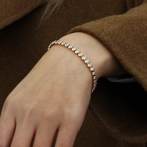 Gros plan d'un bracelet de tennis doré avec oxydes de zirconium ovales au poignet