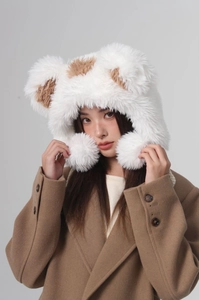 Detail of plush bear ear bucket hat with white and brown pom-poms and fuzzy texture