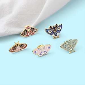 Set of 5 enamel butterfly pins in various colors on a light blue background