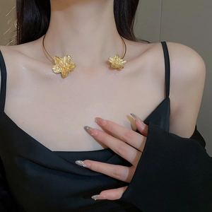 Detailed close-up of golden metal flower choker with textured petals on female neck