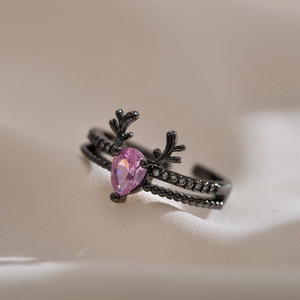 Detailed close-up of double-layer black ring with pink teardrop gem and deer antler accents