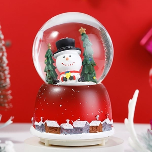 Close-up of a Christmas crystal ball featuring a snowman, a tree, and a red base