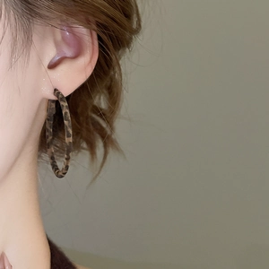 Gros plan de boucles d'oreilles créoles à motif léopard portées par un mannequin en style rétro