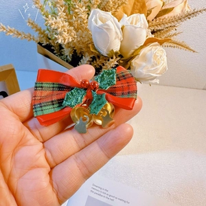 Detail of a Christmas bow hair clip with red-green plaid ribbon and gold bells