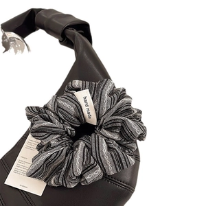 Classic black and white striped scrunchie with handmade tag on a leather bag handle
