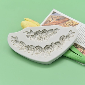 White silicone rose flower mold for DIY fondant and cake decoration on green background