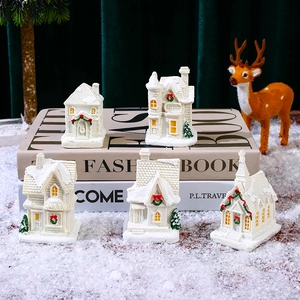 Detail of five white light-up resin Christmas village houses with warm LED windows