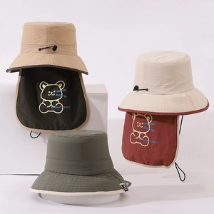 Detail of kids sun hats with neck flaps in khaki, beige and green featuring bear embroidery
