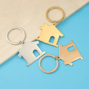 Three-color hollow house keychains in silver, gold, and rose gold finishes on a stone base