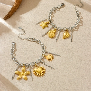 Silver stainless steel chain bracelet with gold sea shell and starfish charms on sand