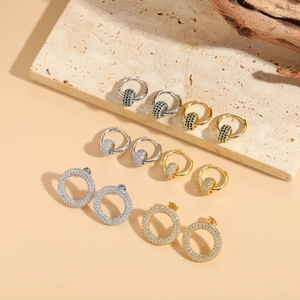 Detailed display of gold and silver circle earrings with paved zircon on textured stone