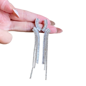 Boucles d'oreilles élégantes à pampilles argentées avec zircons tenues à la main