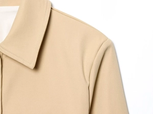 Detailed close-up of khaki jacket collar and shoulder with neat stitching texture