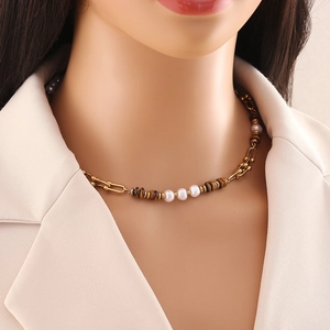 Close-up of golden layered necklace with brown tiger eye beads and white pearls on model