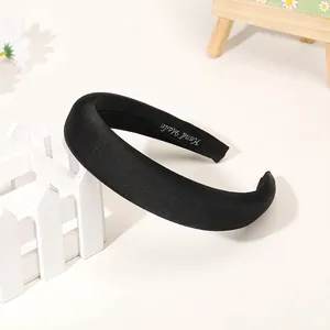 Close-up of black satin padded headband with handmade label and soft texture