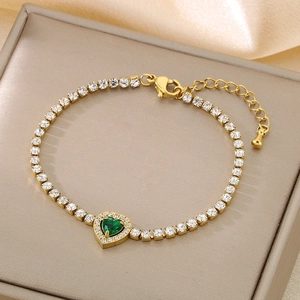 Detail of gold tennis bracelet with green heart gemstone and white zircons